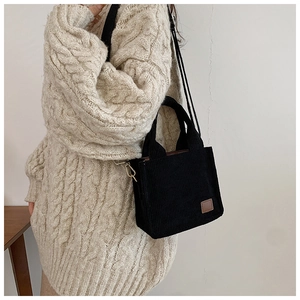 Detail der schwarzen Cord-Mini-Handtasche mit strukturiertem Stoff und Lederetikett