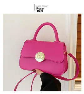 Detail of rose red crossbody bag with matte finish and circular metal buckle decoration