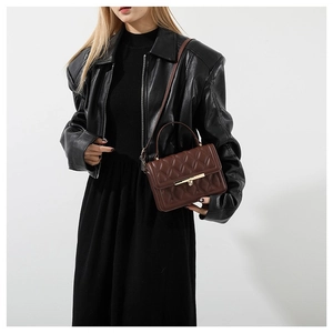 Deep brown quilted crossbody bag with gold hardware shown on a model in a studio set