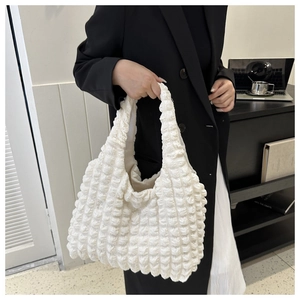 Detail of soft 3D popcorn texture on ivory white nylon tote bag carried by model