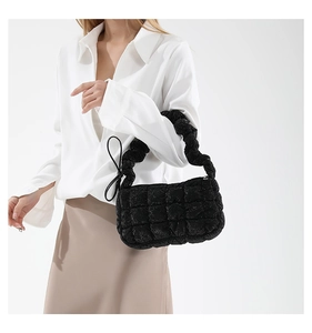 Detail of black quilted puffer bag with pleated texture and shimmering fabric finish