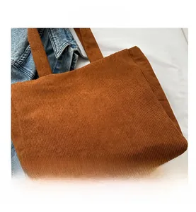 Close-up of brown corduroy tote bag showing vertical stripe texture and shoulder strap