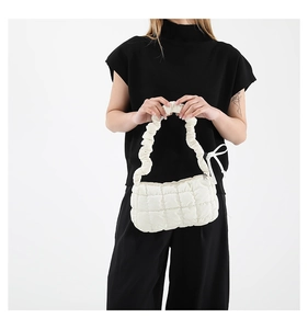 Detail of white quilted cloud bag featuring pleated handles and ivory finish