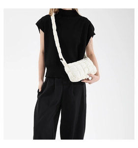 Detail of white quilted puffy shoulder bag with wide padded strap on model