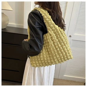 Detailed close-up of a bright yellow tote bag with unique bubble texture and pleated fabric
