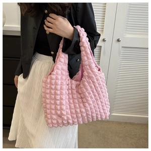 Close-up of pink popcorn fabric tote bag with soft bubble texture on a female model