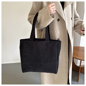 Detail of black corduroy tote bag showing ribbed texture and large capacity style