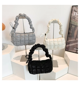 Three quilted square bags in gray, white, and black with unique pleated handles and zippers
