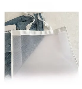 Detailed macro view of white breathable mesh tote bag laying on blue denim jacket fabric