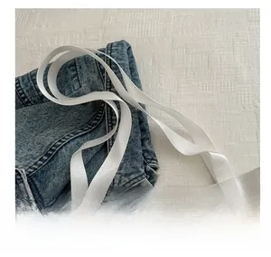 Detail of light blue denim tote with white woven handles and reinforced stitching