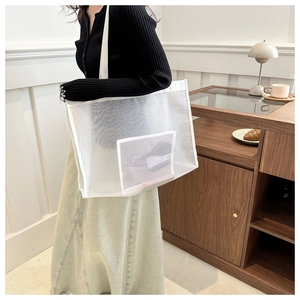 Detailed shot of large white mesh tote bag with inner pocket on a model's shoulder