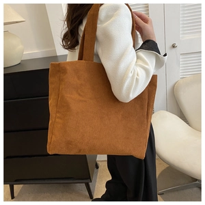 Close-up of brown corduroy tote bag with thick ribbed texture worn by a model