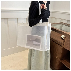Detail of white mesh tote bag featuring a minimalist portrait print and semi-transparent fabric
