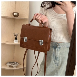 Detail of vintage brown matte leather satchel with dual silver metallic buckles and top handle