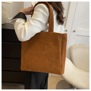 Caramel brown corduroy tote bag with large capacity, shown on model in modern room