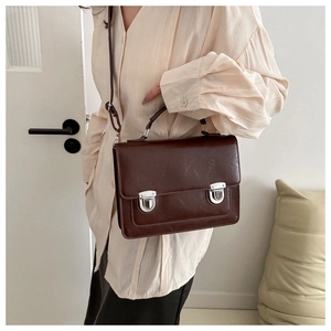 Detail of dark brown vintage satchel bag featuring silver metal buckles and leather texture