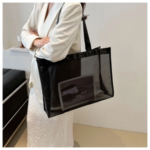 Detail of black mesh tote bag with grey pocket shown on model in a minimalist setting