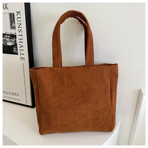 Detail shot of brown corduroy tote bag showing vertical ribbed texture and retro design