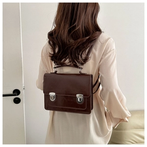 Detail of dark brown retro satchel backpack showing the back carry effect on a model