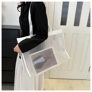 Close-up of white mesh tote bag showing transparent fabric texture and wide strap