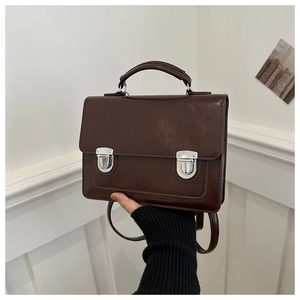 Detail of vintage brown leather briefcase bag with dual silver buckles and top handle