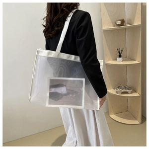 Detail of white mesh tote bag showing fine texture and wide shoulder strap on model