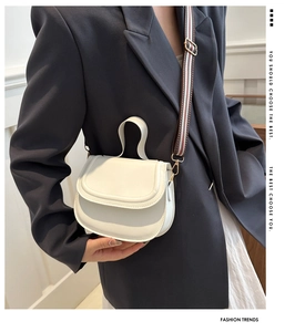 Fashionable white saddle bag with wide striped shoulder strap shown on a female model