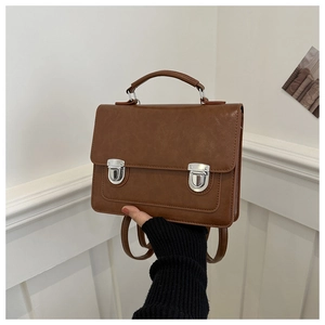 Detail of vintage brown shoulder bag with dual metal snap closures and precise stitching