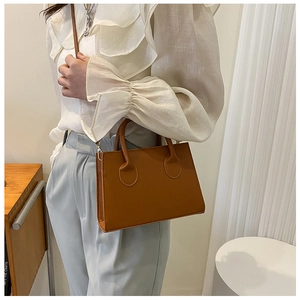 Brown synthetic leather mini tote bag shown on a model in a minimalist setting