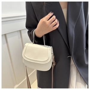 Detail of a white saddle bag with wide striped woven strap on a black blazer