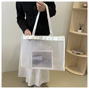 Close-up of white mesh tote bag featuring reinforced straps and interior decorative card