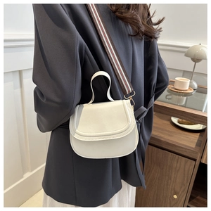 Detailed side view of white leather saddle bag with vintage striped woven strap