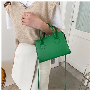 Detail of emerald green leather tote bag with round handles and silver chain link