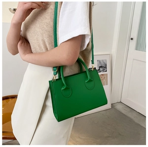 Détail d'un sac à main rectangulaire vert vif en cuir avec crochets métalliques dorés