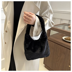 Détail du sac hobo noir en fausse fourrure pailletée porté sur un manteau beige
