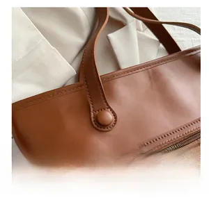 Dettaglio borsa tote in pelle martellata marrone con tasca zip e finiture metalliche dorate