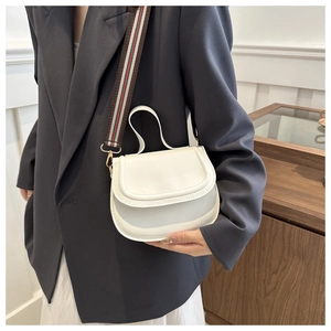 Close-up of white saddle bag with iconic red and green striped shoulder strap on model