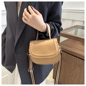Detail of khaki saddle bag with stylish striped wide shoulder strap worn by a model