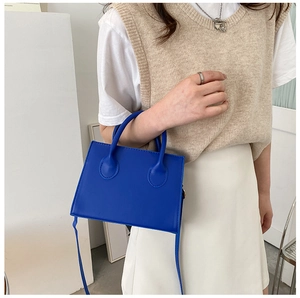 Détail du sac à main bleu Klein en cuir avec fine bandoulière porté sur un mannequin