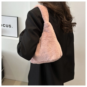 Gros plan du sac à bandoulière en peluche rose porté avec une veste noire chic
