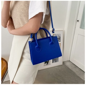 Detail of royal blue leather handbag with golden hardware and adjustable shoulder strap