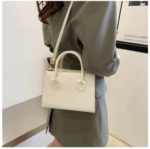 Minimalist white leather handbag styled on a shoulder with a chic blazer for daily commute