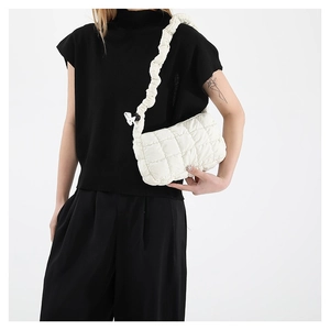 Minimalist white quilted shoulder bag with fluffy cloud strap shown on a model