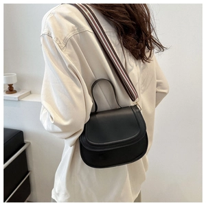 Detail of half-moon saddle bag showing striped wide strap and matte black leather finish