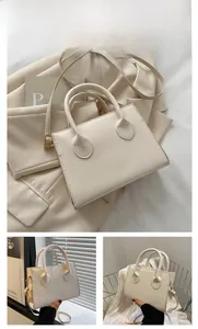 Detail of white rectangular leather handbag with rounded handle and metal strap buckle