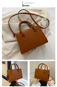 Detail view of brown faux leather square handbag with top handle and adjustable strap