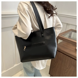Vista posteriore della modella con borsa tote minimalista in pelle nera con tasca con zip