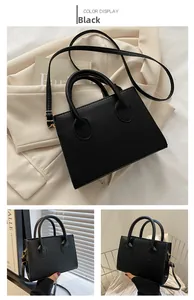 Close-up of black matte faux leather square bag with gold hardware and top handles