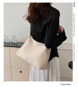 Detail of beige pebbled leather tote bag showing fine texture and soft material on model