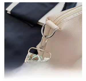 Detail of silver hardware and ethnic woven shoulder strap on beige leather tote